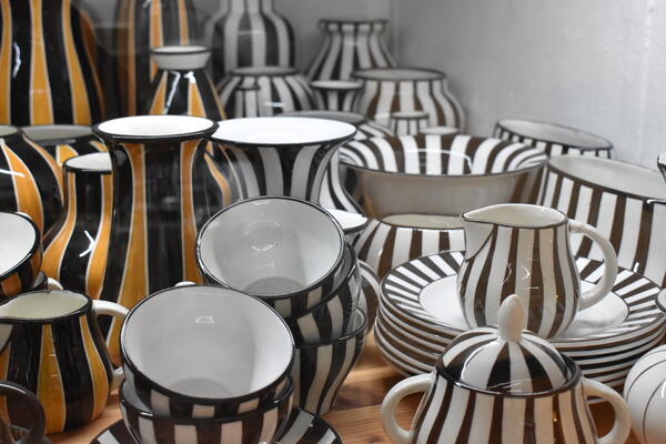 Schwarz-weiß gestreiftes Geschirr ind mehreren Varianten wie Teller, Tassen und Vasen.