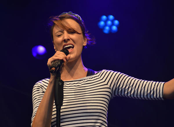 Die Sängerin singt ausdrucksvoll bei dezenter, blauer Beleuchtung auf der Konzertbühne des plattdeutschen Festivals.