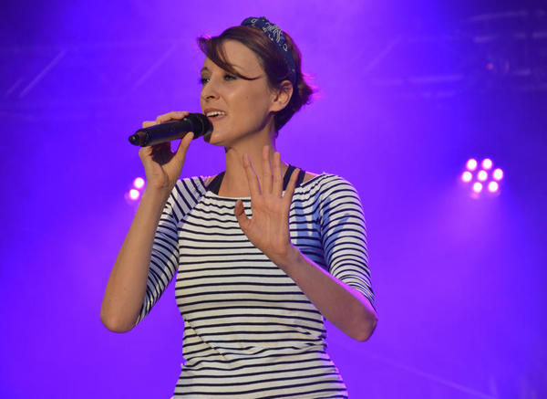 Die Sängerin singt ausdrucksvoll bei dezenter, blauer Beleuchtung auf der Konzertbühne.