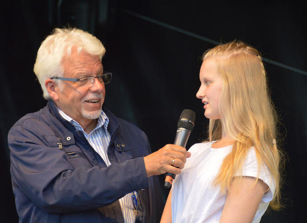 Der Rundfunk Moderator befragt die Jugendliche auf der Bühne des plattdeutschen Festivals.