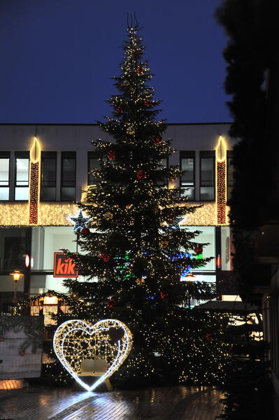 Mit Weihnachtsbeleuchtung erhellte Innenstadt in Elmshorn. Im Vordergrund eine große beleuchtete Weihnachtstanne.